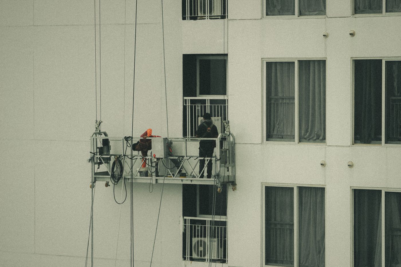 Filipino facilities professionals working on a commercial building facade with their faces turned away